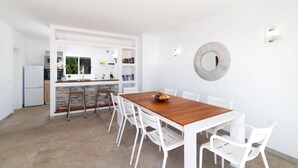 Una cocina moderna con armarios blancos, horno empotrado y refrigerador.
