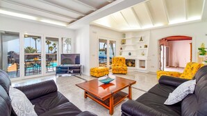 A spacious living room with a pool view, a fireplace, and a dining area. - Villa Nino by Villa Plus (Puerto del Carmen)