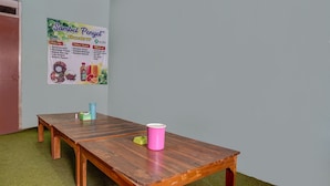 Una mesa de madera con una taza rosa y un recipiente verde, sobre una alfombra verde.