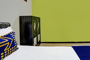 Un lit avec une literie blanche et bleue, un mur vert et une armoire en bois avec un miroir.