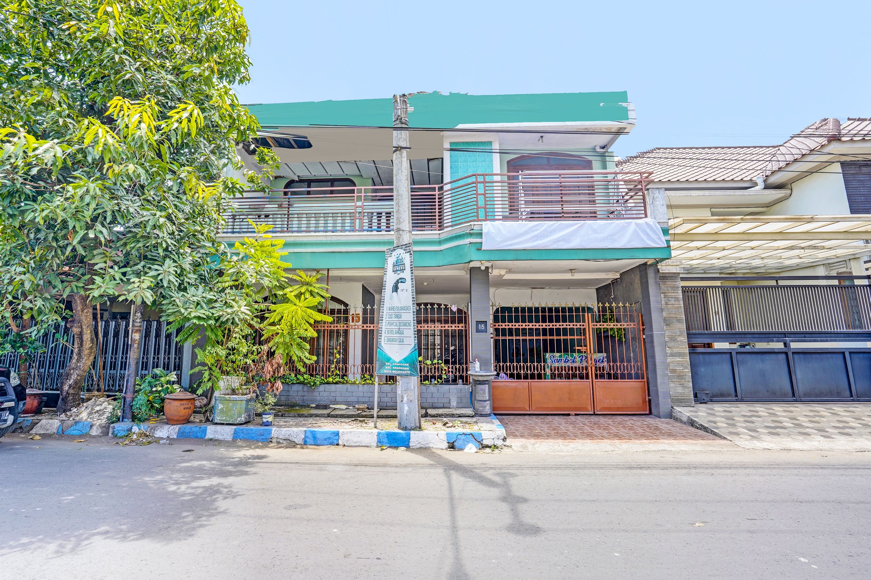 A two-story building with a balcony, a signboard, and a gated entrance.