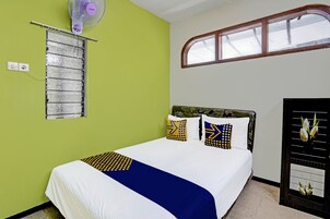Un dormitorio con cama, ventana, ventilador de pared y espejo.
