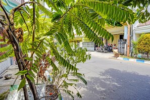 Une vue de rue avec une rangée de motos garées, un bâtiment avec une enseigne jaune et un arbre aux feuilles vertes.