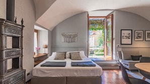 A bedroom with a large bed, a wooden dresser, a sofa, and a dining table. - Atelier Dell Artista by Wonderful Italy (Varenna)
