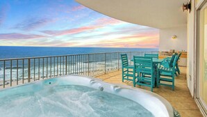 Un balcón con jacuzzi, sillas y vistas a la playa y al océano.