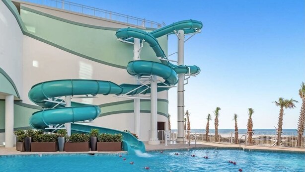 Una piscina con varias toboganes y una vista despejada del océano.