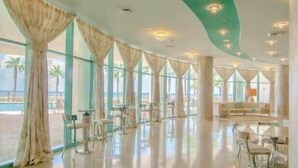 Un espacio interior amplio con grandes ventanales, vista a la piscina y una zona de estar.