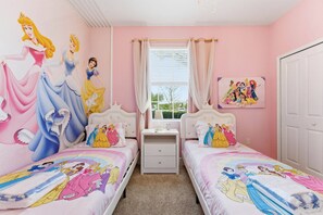 Ein Schlafzimmer mit zwei Betten, jeweils mit Bettwäsche im Stil der Disney-Prinzessinnen.