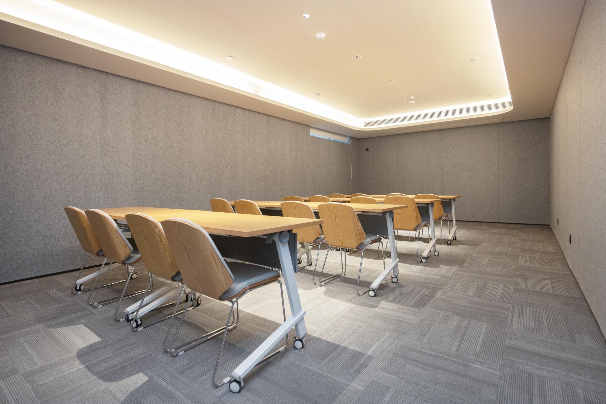 Sala de conferências com várias mesas e cadeiras, equipada com rodízios para facilitar a movimentação.