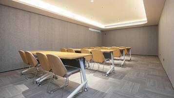 Sala de conferências com várias mesas e cadeiras, equipada com rodízios para facilitar a movimentação.