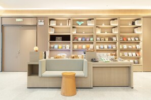 A modern reception area with a sofa, a wooden stool, and a wall of bookshelves.