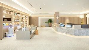 Ein moderner Empfangsbereich mit einer Marmor-Theke, einer großen Pflanze in einem Topf und einem ordentlich organisierten Bücherregal.