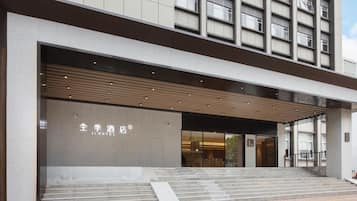 A modern hotel entrance with a large glass facade, a wooden overhang, and a sign in both Chinese and English.