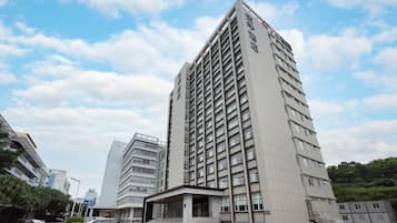 Edifício de hotel com vários andares, entrada destacada e céu claro.