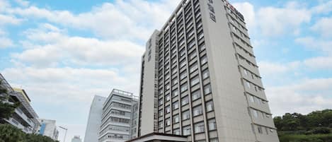 Un edificio de hotel de varios pisos con una entrada destacada y cielo despejado.