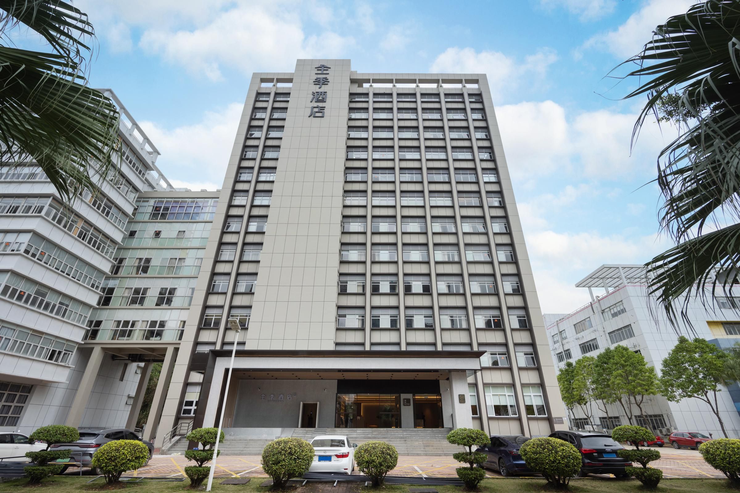 Un hôtel à plusieurs étages, doté d’une entrée imposante et d’un espace de stationnement situé à l’avant.