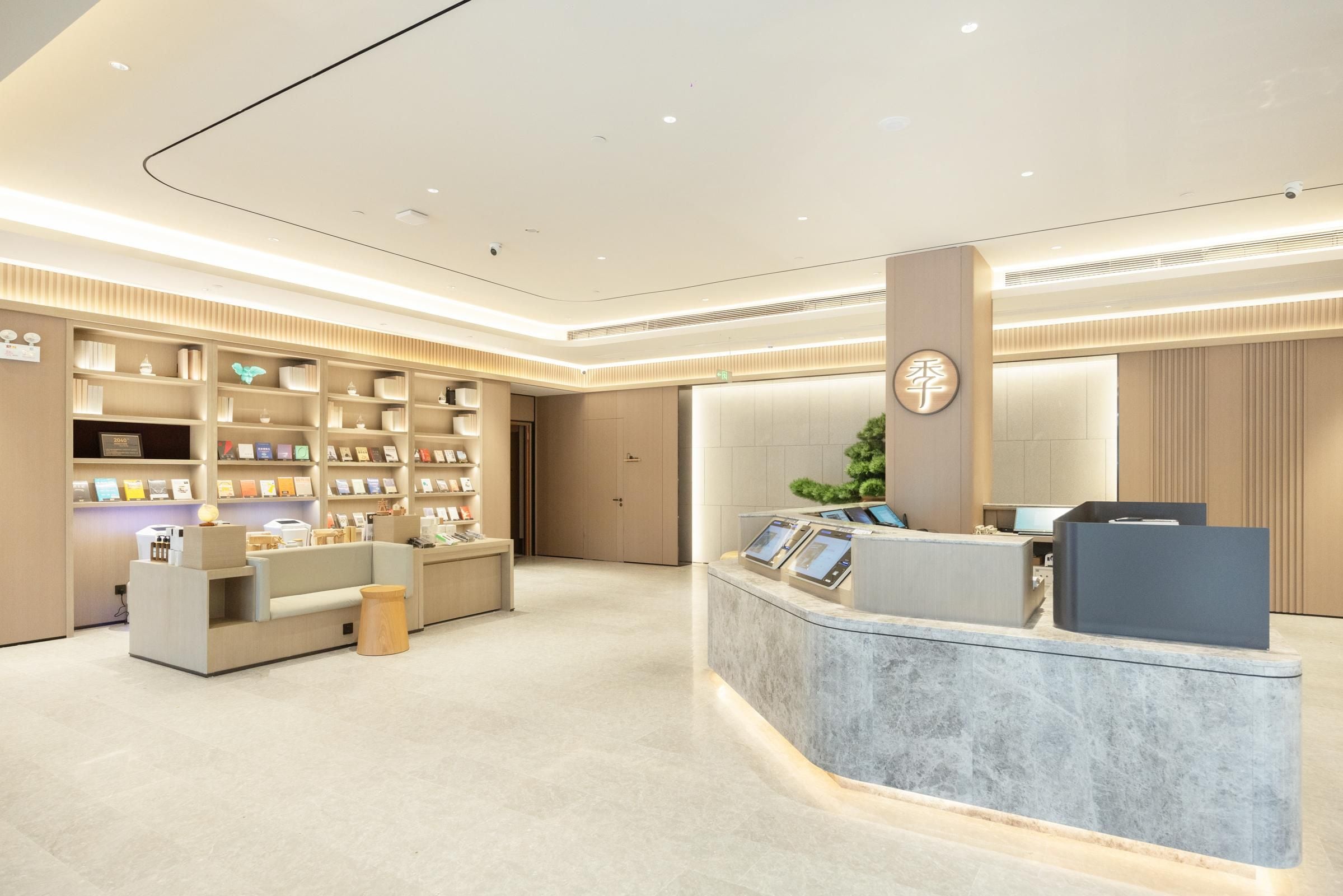 Un hall d’hôtel moderne comprenant un comptoir d’accueil, un espace salon et un mur entier recouvert d’étagères à livres.
