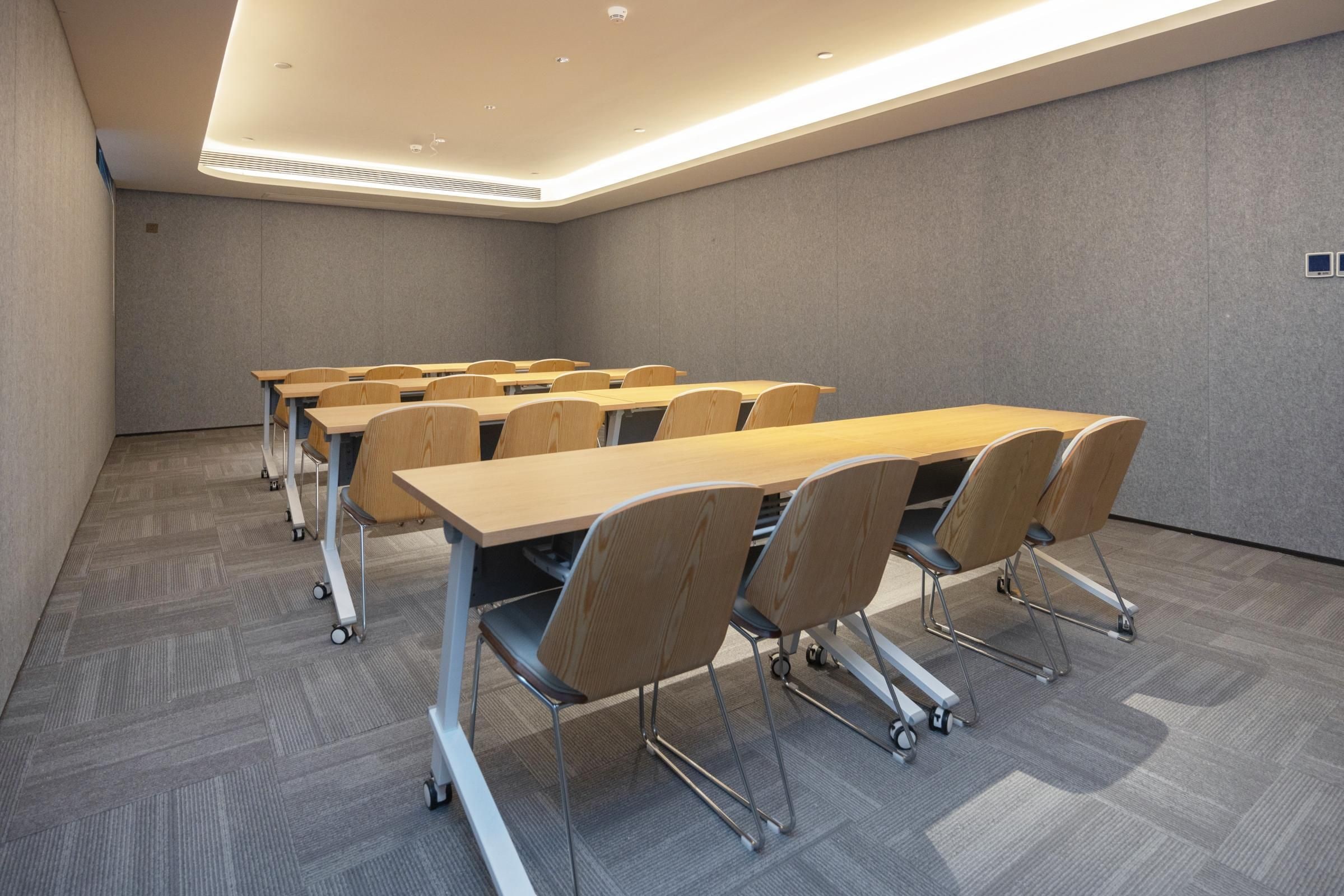 A conference room with multiple tables and chairs, carpeted flooring, and a ceiling with recessed lighting.
