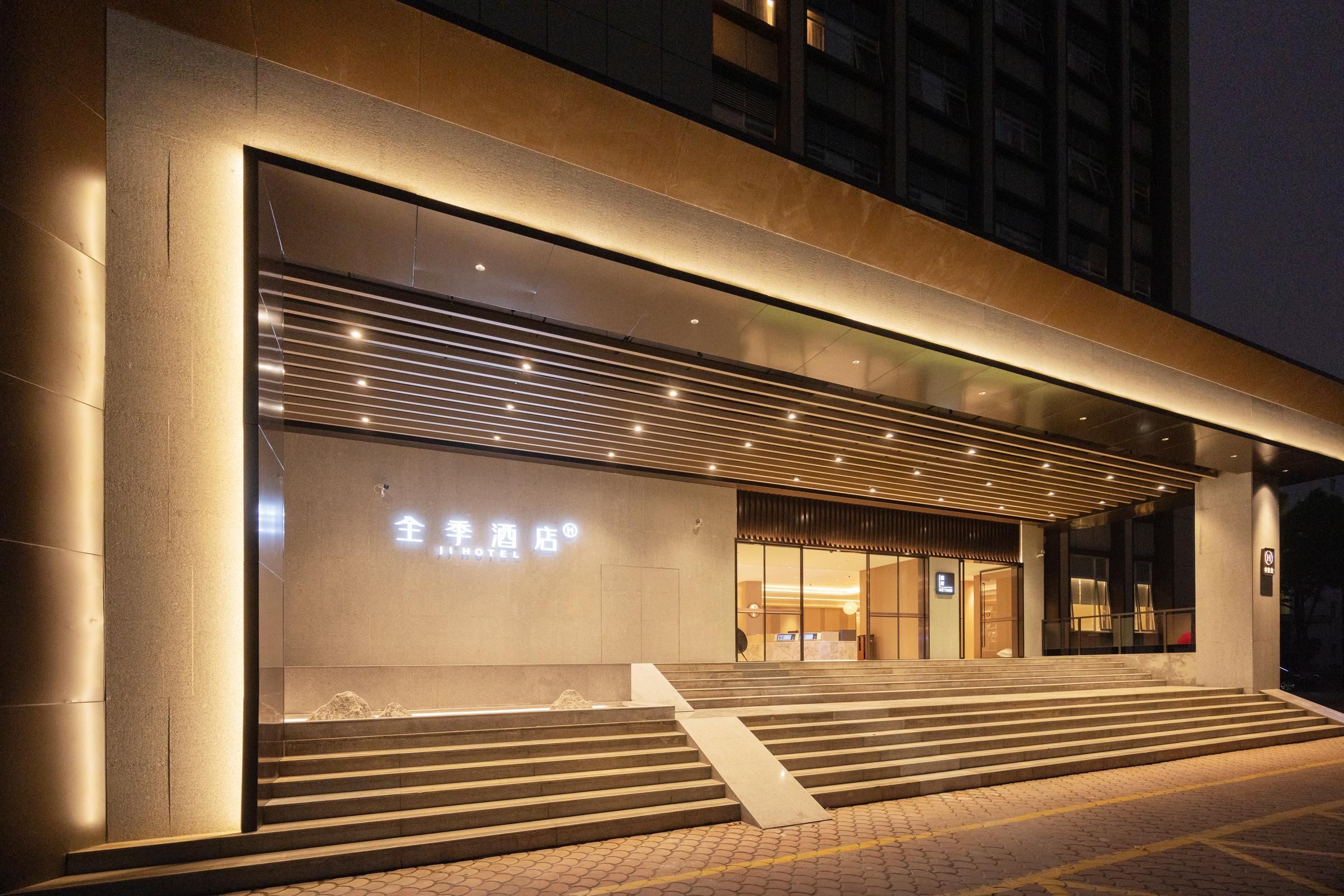 Entrada de hotel con diseño moderno, que presenta un letrero iluminado grande y un conjunto de escalones amplios que conducen a la entrada.