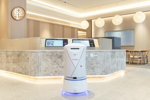 A hotel reception area with a modern design, featuring a reception desk with digital displays, a robot, and a seating area with chairs. - Ji Hotel Shenzhen Nanshan Technical Park (Shenzhen)