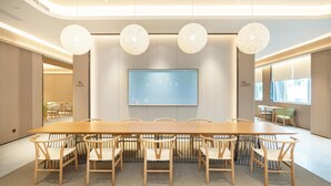Ein Konferenzraum mit einem langen Tisch, sechs Stühlen und drei hängenden Kugelleuchten.