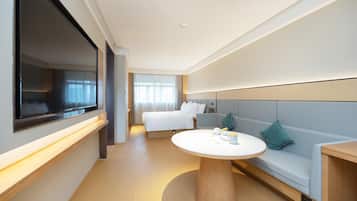 Una habitación de hotel con una cama, un sofá, una mesa redonda y un televisor.