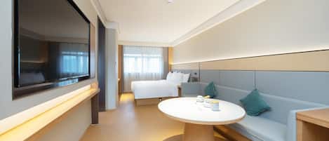 Una habitación de hotel con una cama, un sofá, una mesa redonda y un televisor.