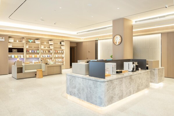 A modern reception area with a marble counter, bookshelves, and a coffee machine.