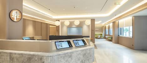 A modern reception area with a marble counter, digital displays, and a large screen.
