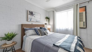 Relax in a serene bedroom with a large bed, a potted plant, and a framed picture.