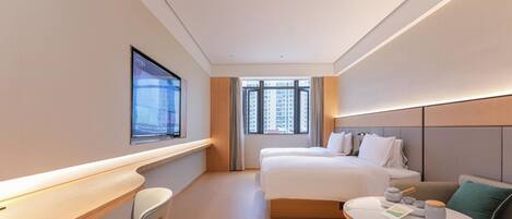 A hotel room with a bed, a desk, a chair, a round table, and a window with a view of buildings.