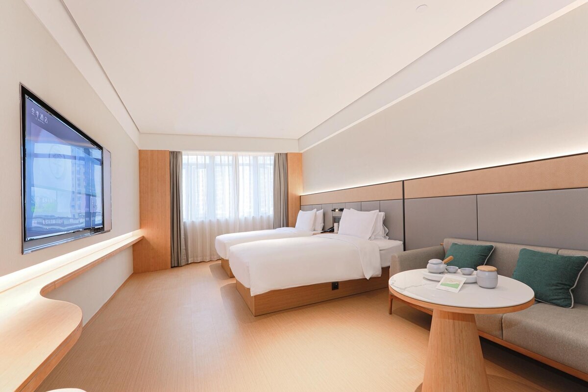 Ein Hotelzimmer mit einem Bett, einer Couch, einem runden Tisch und einem an der Wand befestigten Fernseher.