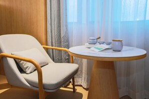Ein Zimmer mit einem Ledersessel, einem kleinen runden Tisch mit Teekanne, Tassen und einer Karte.