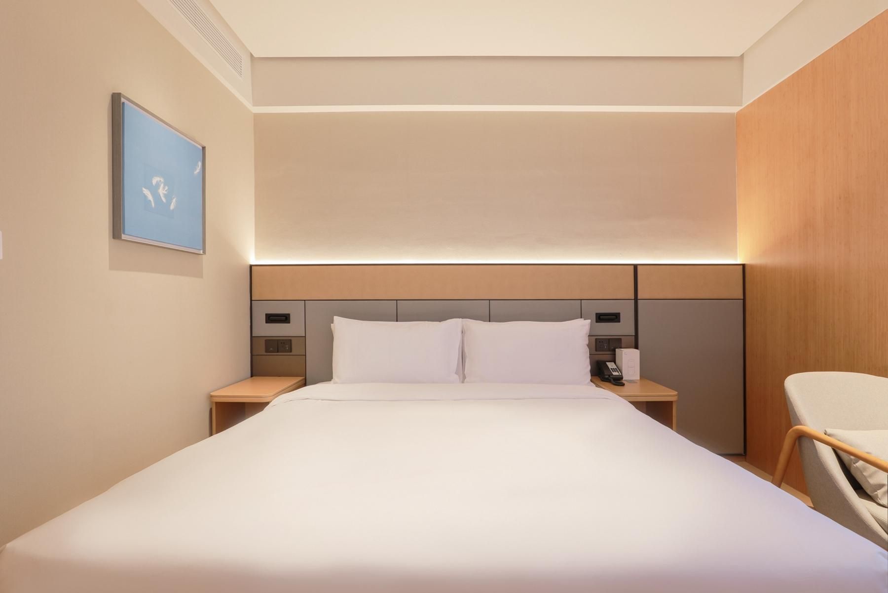 A hotel room with a large bed, bedside tables, a desk, and a chair.
