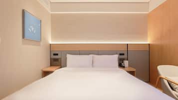 A hotel room with a large bed, bedside tables, a desk, and a chair.