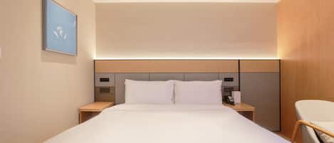 A hotel room with a large bed, bedside tables, a desk, and a chair.