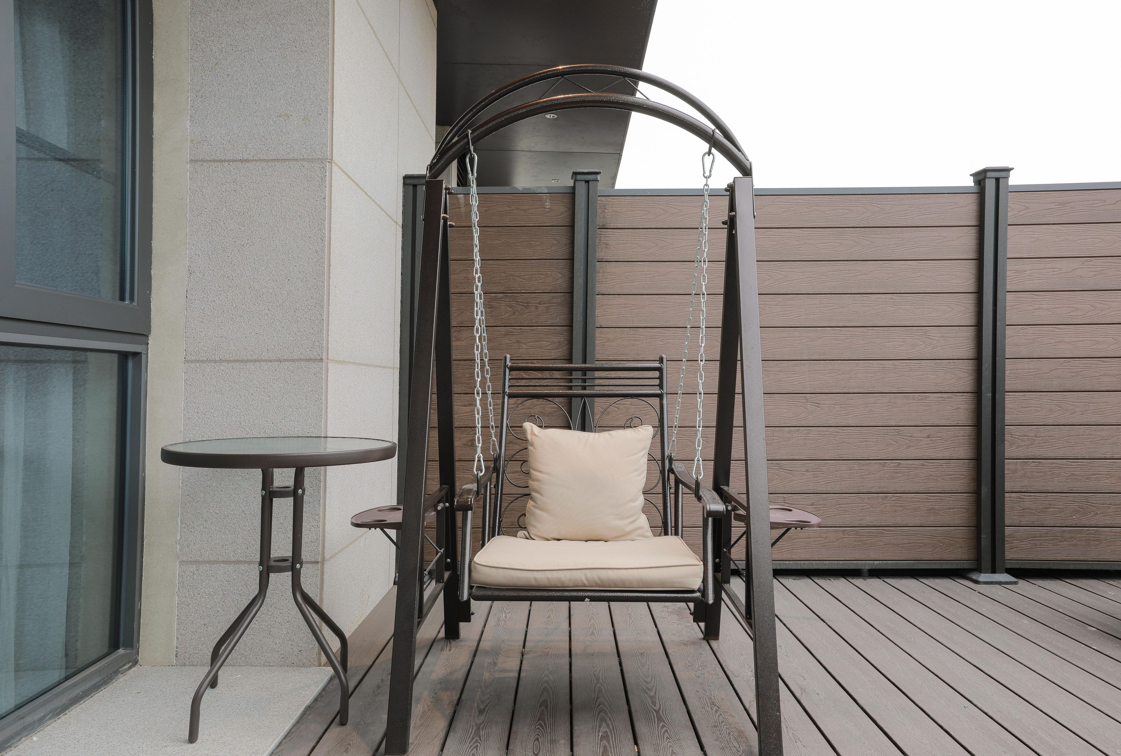 A wooden deck with a swing chair and a small table.