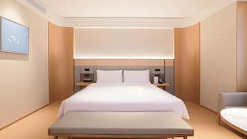 A modern hotel room with a large bed, bedside tables, a bench, and a view of the sky.