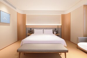 Une chambre d’hôtel moderne avec un grand lit, des tables de chevet, un banc et une vue sur le ciel.