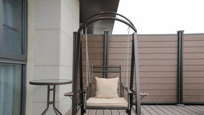 Een houten terras met een hangstoel en een kleine tafel.