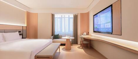 Una habitación de hotel con una cama grande, un escritorio, una silla y un televisor montado en la pared.