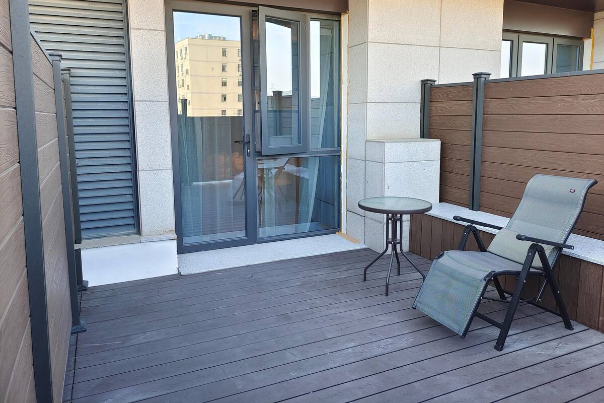 Un balcón con puerta de cristal, una mesita redonda y una silla.
