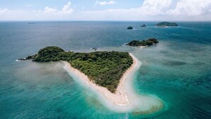 An aerial view of a tropical island with a narrow beach, surrounded by clear turquoise waters and lush greenery. - Belle Escapes Drift Beachfront Resort Suite 3409 (Palm Cove)
