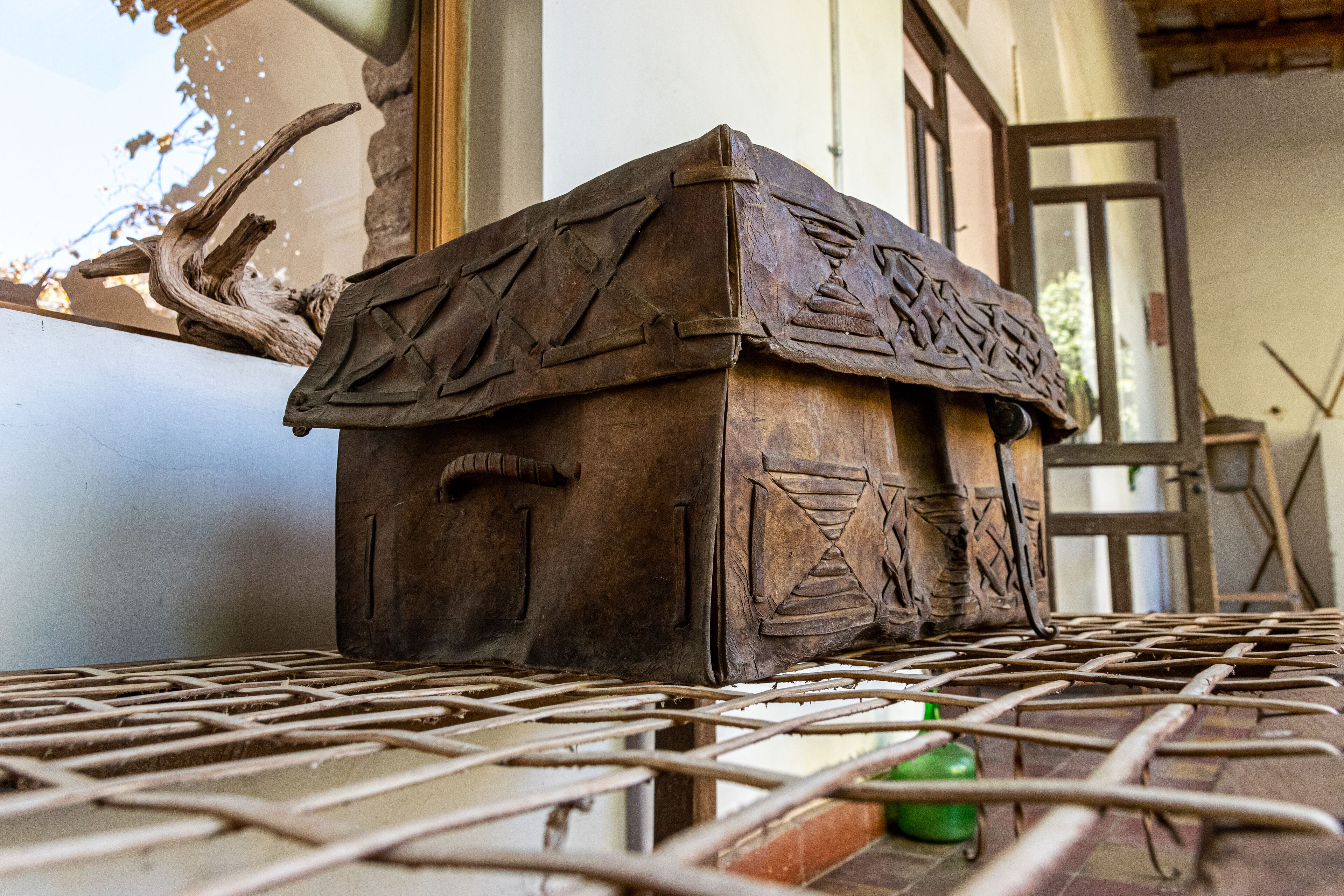 A rustic wooden chest with intricate carvings, placed on a metal table outdoors.