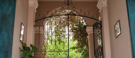 A hallway with a checkered floor, a wrought iron gate, and potted plants.