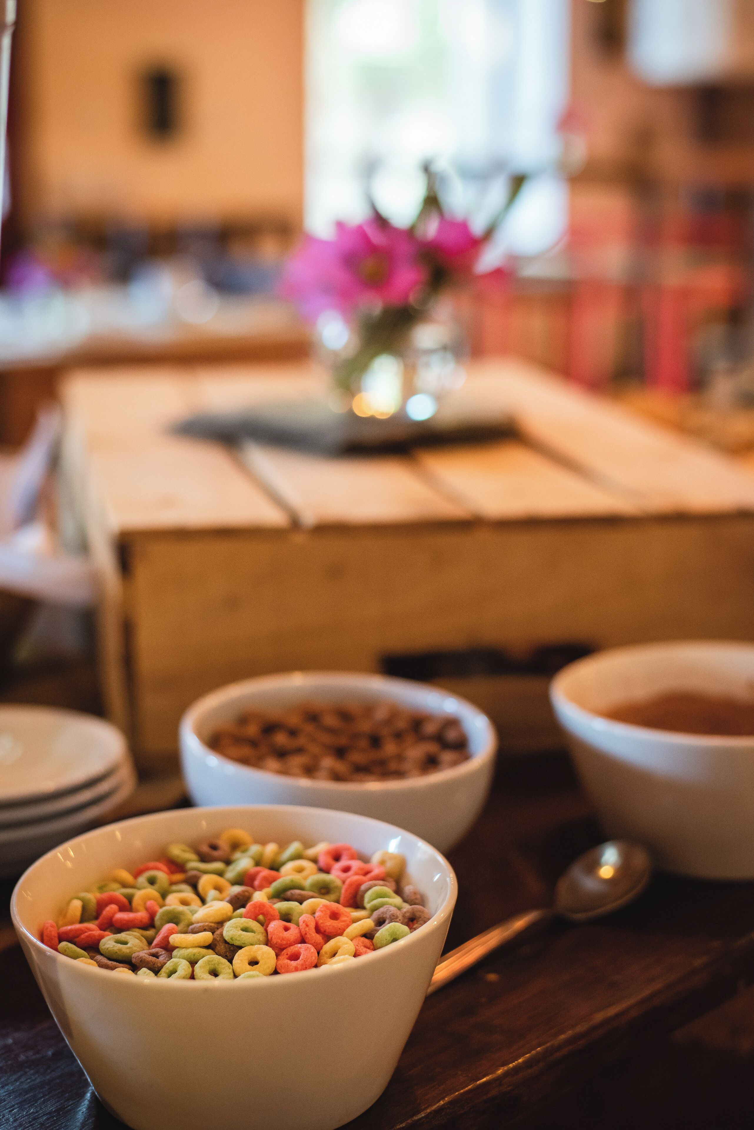 A dining table with bowls of cereal and a spoon.