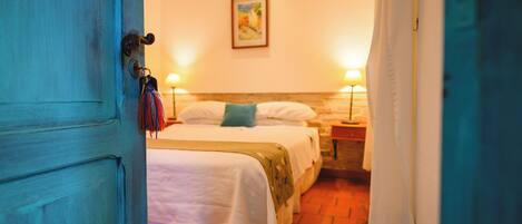A room with two beds, a painting on the wall, and a door with a key hanging on it.