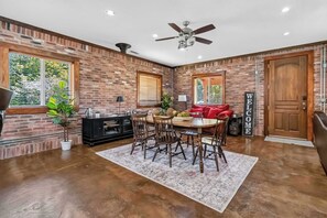 A dining area with a brick wall, a ceiling fan, and a 'WELCOME' sign. - Beaver Lake House: Walk to Marina (Lowell)