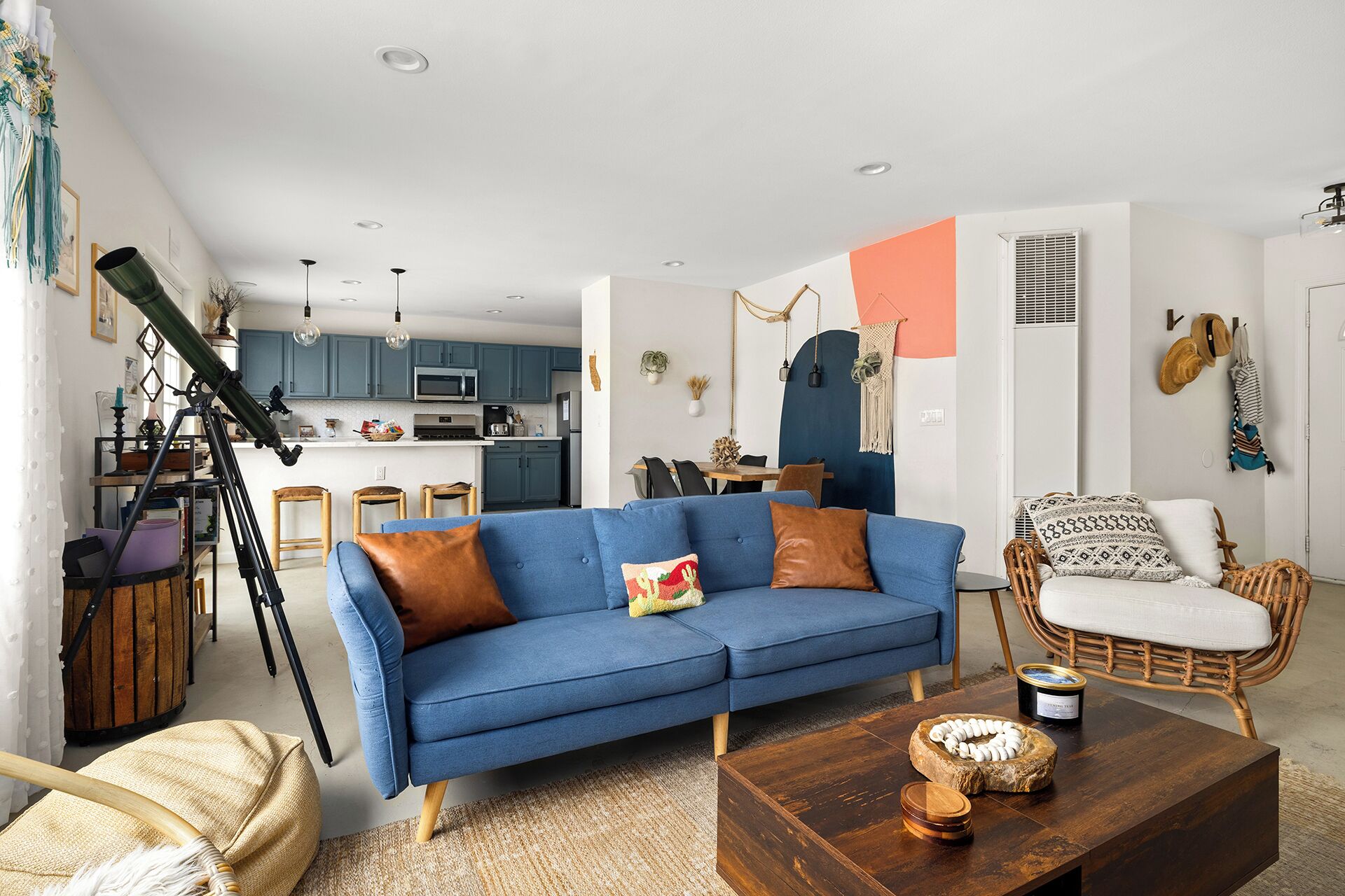 Una sala de estar moderna con un sofá azul, una mesa de centro de madera y una silla de mimbre.