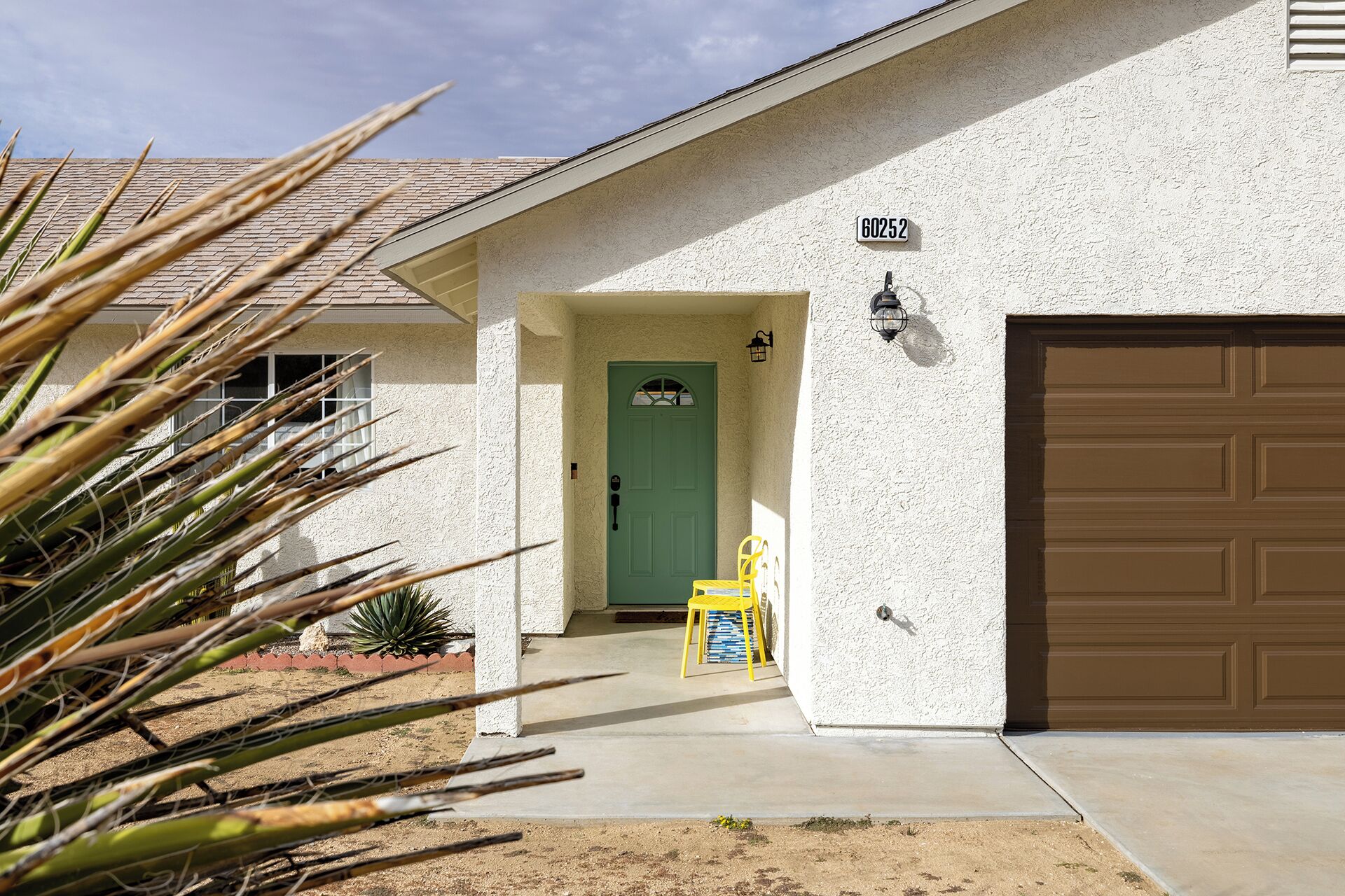 A house with a green door, a garage door, and a number sign.
